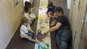 ein Erzieher malt mit vier Kindern