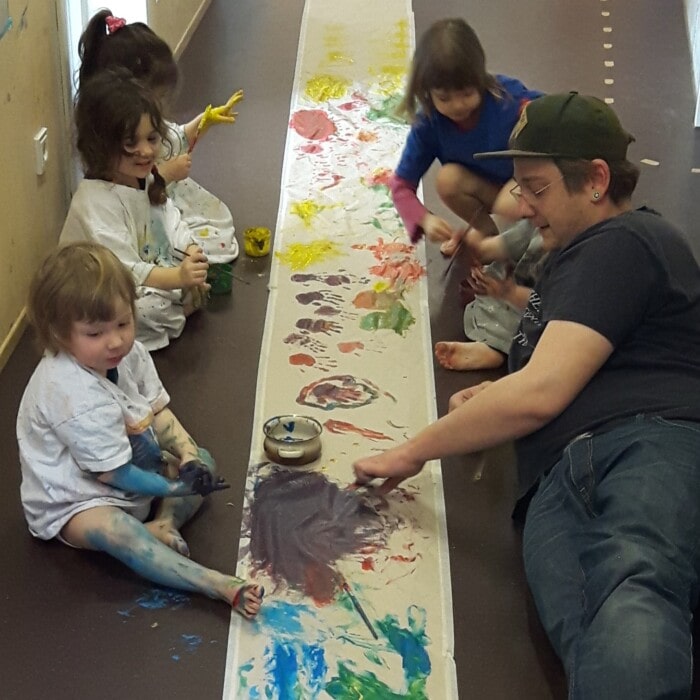 ein Erzieher malt mit vier Kindern
