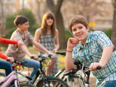 Junge stützt sich auf seinen Fahrradlenker und lächelt in die Kamera.