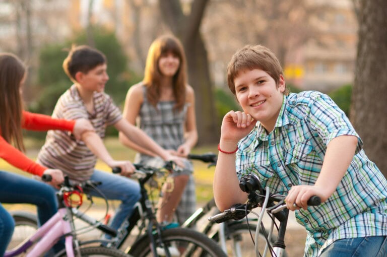 Junge stützt sich auf seinen Fahrradlenker und lächelt in die Kamera.