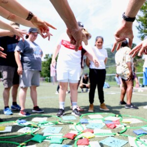 Hände zeigen auf ein Spiel auf dem Boden beim element-i Sommerfest